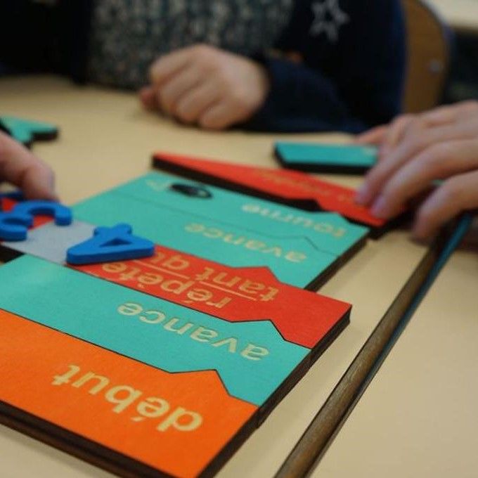 photographie de mains d'enfants tenant des nombres et des bulles de programmation en bois